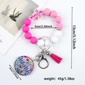 Silicone bead keychain bracelet with cross charm, magenta tassel, and mama floral tag.