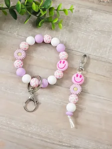 Detailansicht eines Silikon-Perlenarmbands mit rosa Smiley-Gesicht und Blumenanhängern