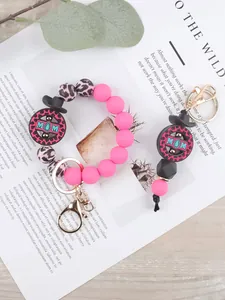 Dettaglio del portachiavi a bracciale in perline di silicone con stampa leopardata e ciondolo MOM