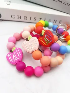 Macro view of colorful silicone beaded keychain with engraved 'TEACH' apple charm