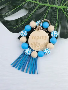 Detail of silicone beaded keychain with mama wood disc and blue leather tassel