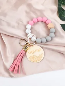 Close-up of pink silicone bead wristlet keychain with 'mama' wooden charm and tassel
