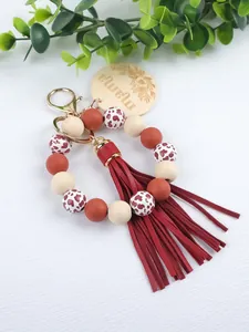 Close-up detail of handmade silicone bead keychain with red tassel and Mama wood tag