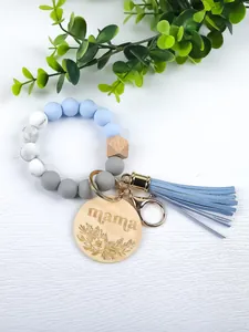 Close-up of silicone and wood bead wristlet keychain with blue tassel and mama charm