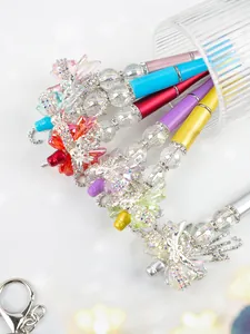 Detailed macro view of colorful beaded pens with sparkling crystal bows and shiny rhinestones.