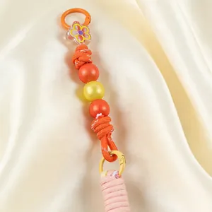 Handmade bead keychain detail featuring an acrylic flower and orange woven rope texture