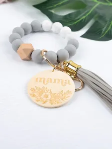 Macro view of silicone and wood bead bracelet keychain featuring a mama engraved wood tag