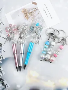 Detailed view of bow beaded ballpoint pens and matching keychains in pink, silver and blue