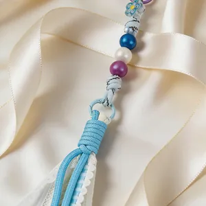 Close-up of a handmade blue tassel keychain with lace and colorful beads on satin ribbon