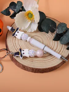 Detailed view of cute Halloween ghost beaded pen and matching keychain on wooden base