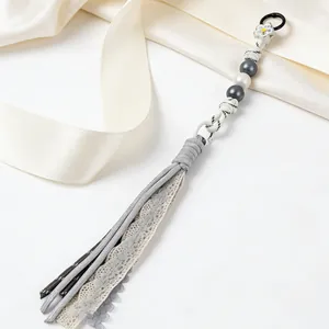 Detailed view of a handmade grey lace tassel bag charm with white and grey beads.
