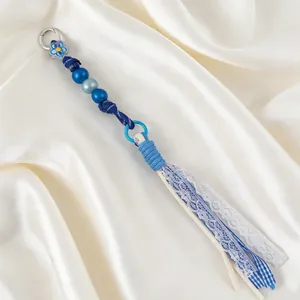 Close-up view of handmade blue beaded tassel keychain with lace and fabric details