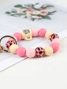Macro view of a silicone beaded keychain with pink leopard print and a small cup charm
