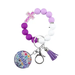 Purple silicone bead wristlet keychain with floral mama tag and tassel cross charm.