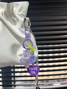 Close-up detail of purple balloon dog keychain with pearls and "LOVE YA" heart charm