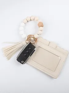 Detail view of off-white silicone beaded wristlet keychain with cream PU leather card holder and tassel.