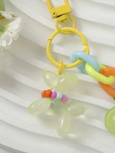 Close-up of yellow glitter balloon dog charm with colorful beaded collar and chain.