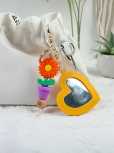 Close-up of yellow PU leather heart mirror keychain with sunflower and pot charms.
