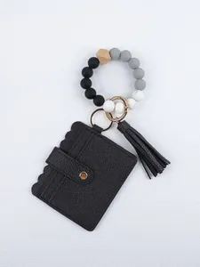 Detail view of black PU card holder with silicone bead wristlet and tassel keychain