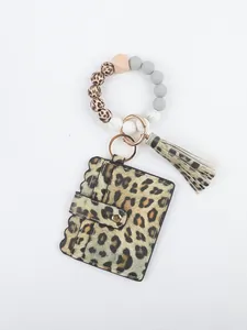 Detail of leopard print card holder with silicone beaded wristlet and tassel pendant.