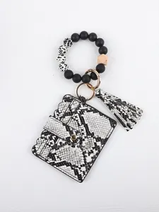 Detail view of snakeskin pattern card holder with beaded bracelet keychain and tassel.