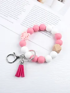 Detail view of a silicone bead wristlet keychain with tassel and wooden bead detail.