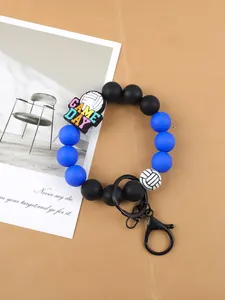 Detalle de pulsera de cuentas de silicona con dije de voleibol y lema GAME DAY.