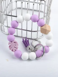Macro view of purple silicone beaded wristlet keychain with tassel and monstera leaf