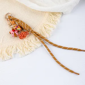 Close-up of handmade braided rope keychain with colorful heart and floral charms.