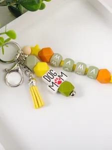 Detailopname van siliconen kralen sleutelhanger met "DOG MOM" tekst en gele kwast.