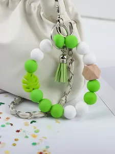 Close-up of green and white silicone beaded keychain with tassel on a white bag