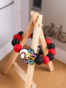 Vista detallada de una pulsera de cuentas de silicona roja y negra con dije de béisbol.