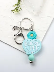 Detail of blue silicone heart keychain with Nurse Life text and daisy charm