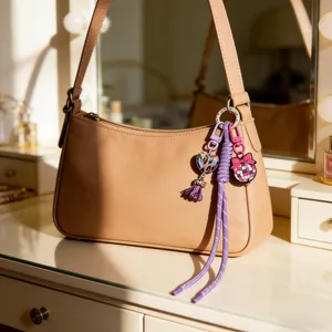 Detailed view of colorful handmade silicone charms hanging on a stylish beige baguette bag