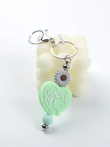 Close-up detail of mint green silicone heart keychain with Nurse Life text and daisy charm.