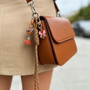 Detail of a colorful silicone heart and braided rope charm on a brown leather bag.