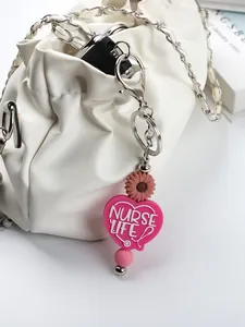 Close-up of pink heart silicone keychain with Nurse Life text hanging on a white bag