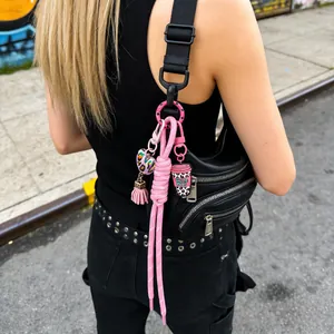 Close-up of pink silicone coffee cup and heart bag charms on a black strap