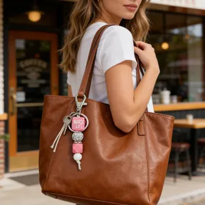Detail of a silicone beaded keychain with NURSE LIFE charm on a brown leather tote bag