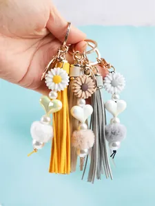 Vue détaillée de porte-clés à pompons faits main avec marguerites en silicone et pompons