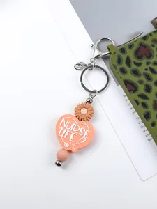 Close-up of pink silicone heart keychain with Nurse Life text and daisy charm
