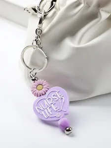 Close-up of purple Nurse Life silicone heart keychain with daisy charm and bead detail.