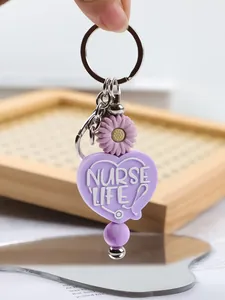 Close-up of a purple silicone keychain with Nurse Life heart and daisy charm.