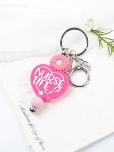 Close-up detail of a pink silicone heart-shaped keychain with Nurse Life text and daisy