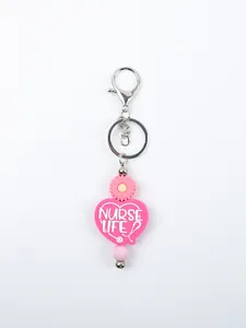 Detailed macro shot of pink silicone heart keychain with nurse life theme and daisy