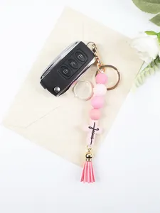 Detailed macro shot of a pink silicone beaded keychain featuring a Jesus cross charm and tassel.