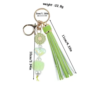 Porte-clés à pompon vert avec marguerite en silicone et pompon en peluche.