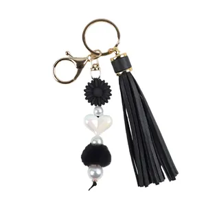 Élégant porte-clés artisanal avec pompon en cuir noir, marguerite en silicone et cœur blanc