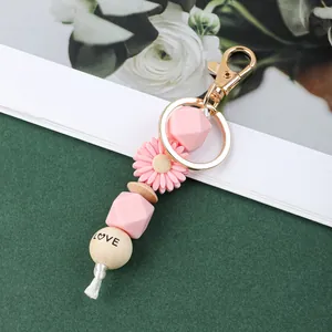 Vue détaillée du porte-clés marguerite en perles de silicone rose avec une perle LOVE en bois