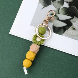 Détail d'un porte-clés en perles de silicone avec marguerite verte et éléments en bois